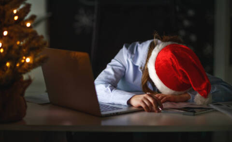 businesswoman freelancer tired, asleep working at computer at Christmas coping with holiday stress