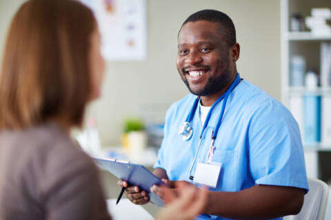 Nursing and Patient Relations Smiling African doctor working with patient in his office