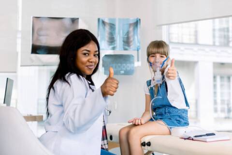 respiratory or nursing career A female nurse and an child are in the medical room and both are giving a thumbs up