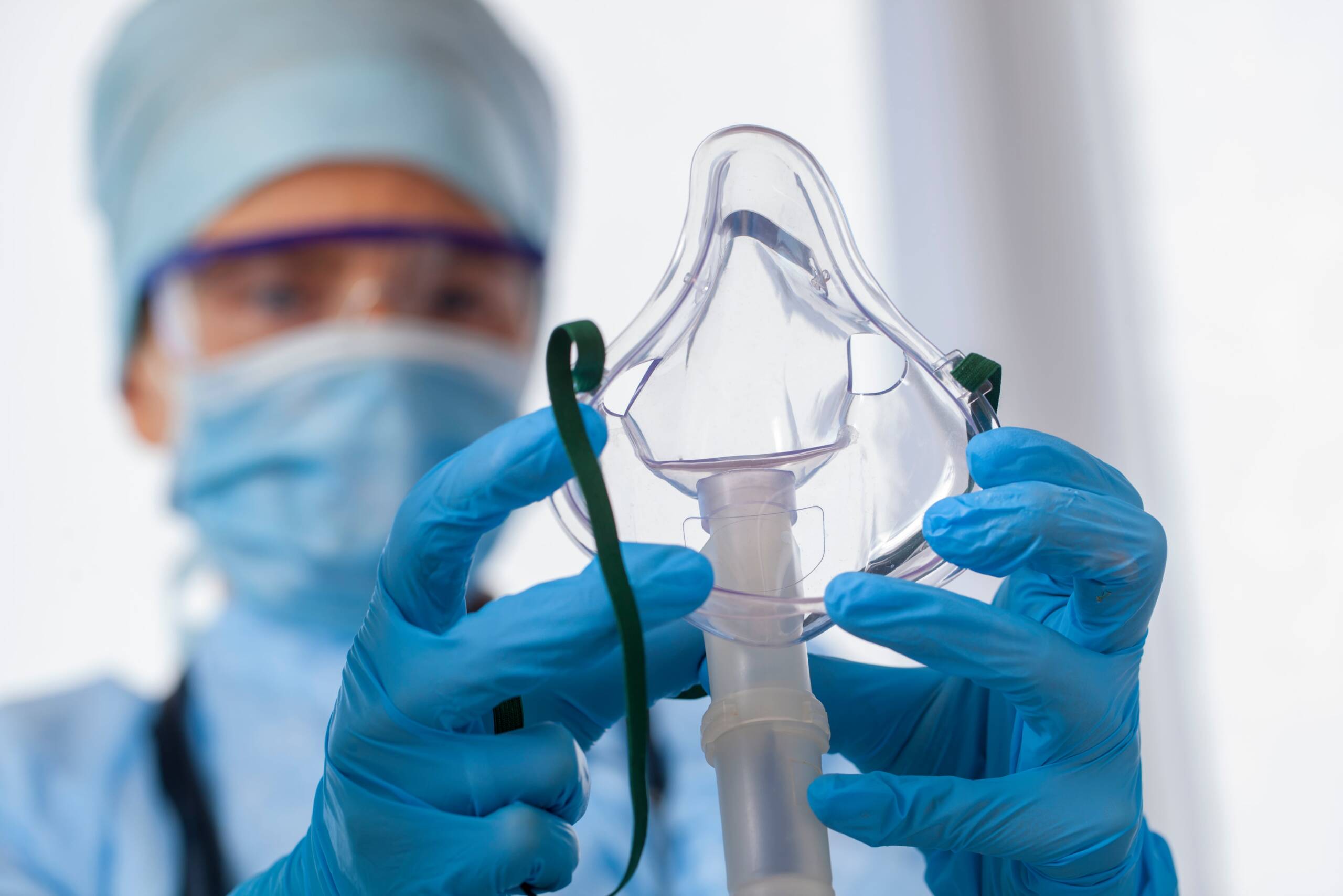 A close up of a respiratory therapist with gloves on and is holding a respiratory mask