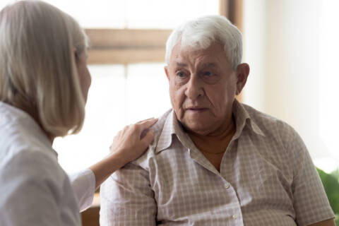 70s man patient and licensed practical nurse communicating indoors